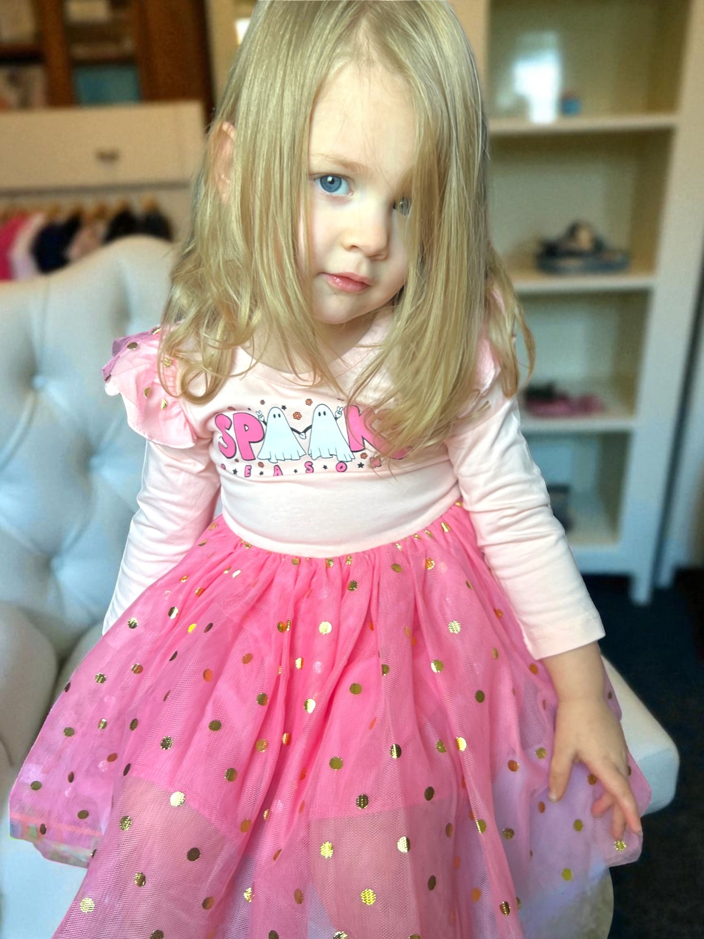 Young girl in a pink dress with gold polka dots indoors