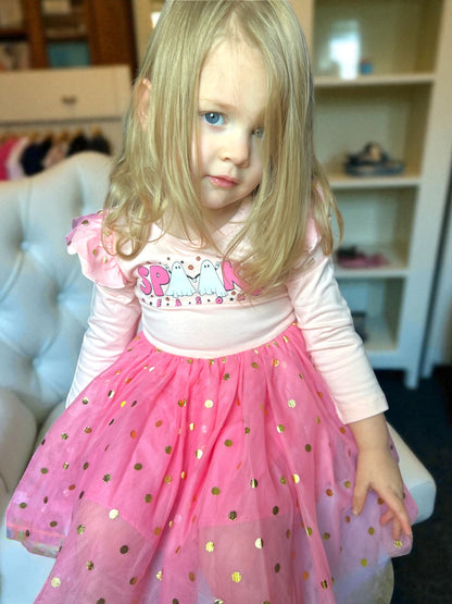 Young girl in a pink dress with gold polka dots indoors